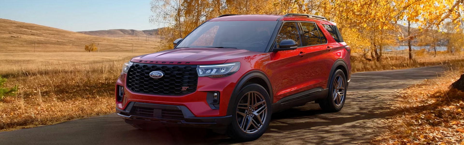 Red Ford Explorer SUV on a scenic road.